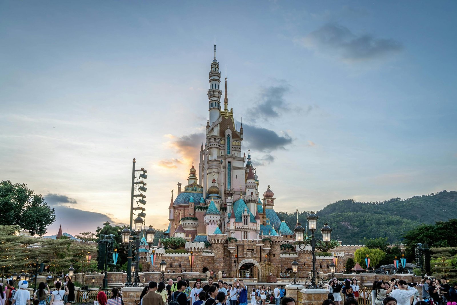 Magical fairytale castle at Hong Kong Disneyland with crowds at sunset.